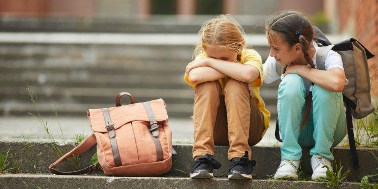 Friend Helping Sad Little Girl in School