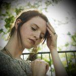 Portrait of sullen young woman with hand on her head in park
