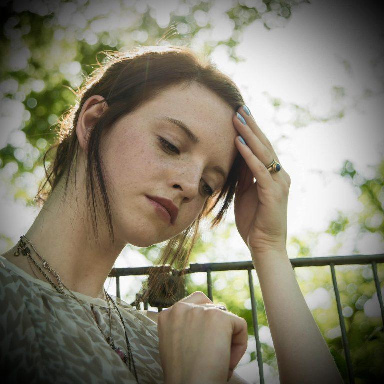 Portrait of sullen young woman with hand on her head in park