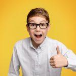 Little boy in glasses showing thumb up gesture
