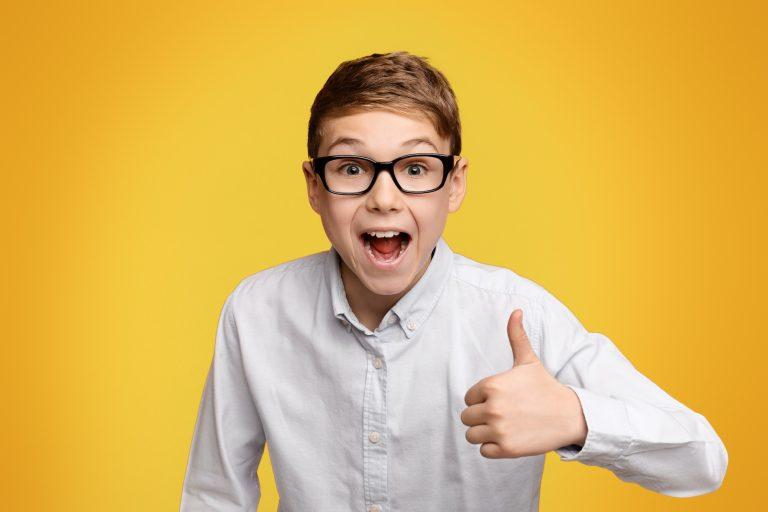 Little boy in glasses showing thumb up gesture