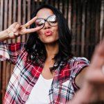 Romantic girl posing on wooden background in sparkle glasses. Fashionable lady making selfie with e