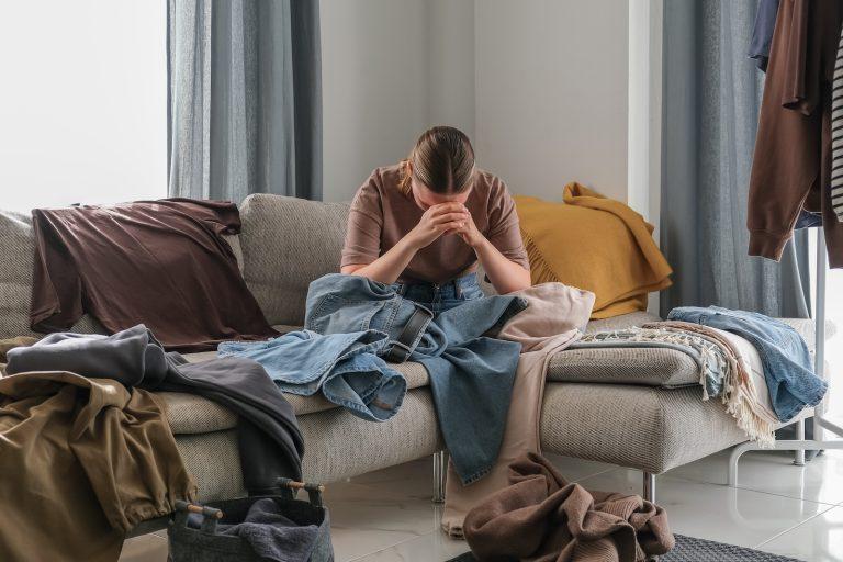 Spring cleaning,second hand,Fast fashion, the girl puts things in order in the closet. A bunch of colorful clothes. The concept of processing, second hand, eco, minimalism, consumption of goods
