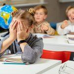 couple students bullying and suppress the guy sitting on the floor. Concept discrimination, racism and negative communication in school and society. Situations in school corridor