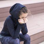 Worried, sad and depressing young woman sits outside