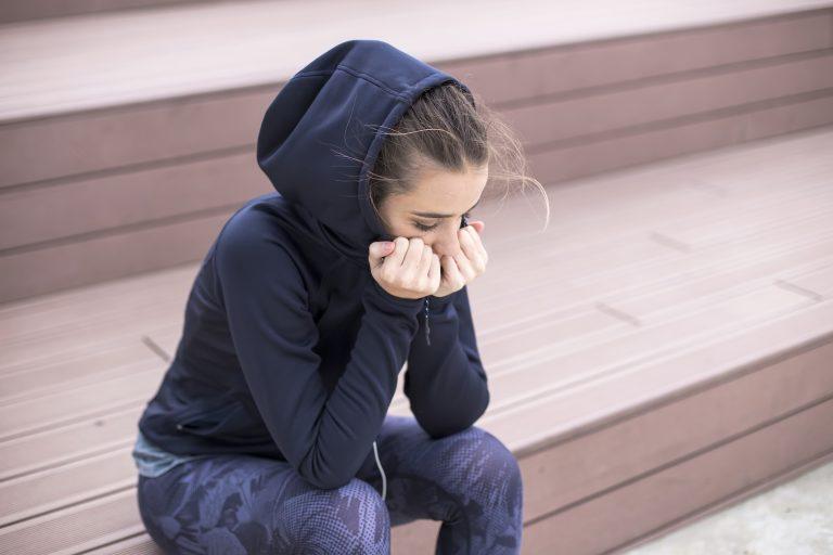 Worried, sad and depressing young woman sits outside