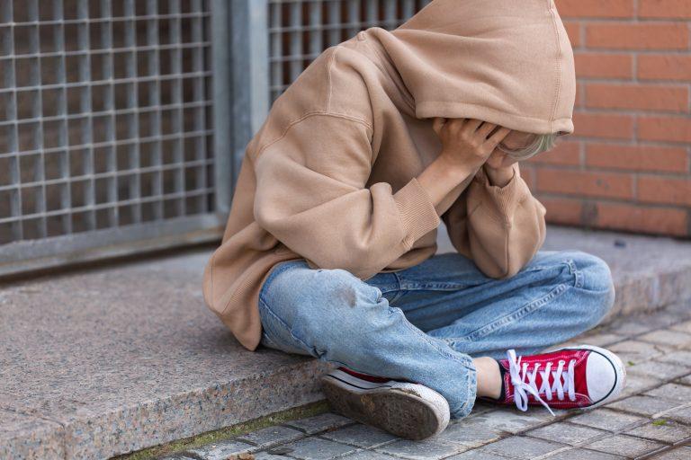 Lonely teenager sitting on the floor outdoors