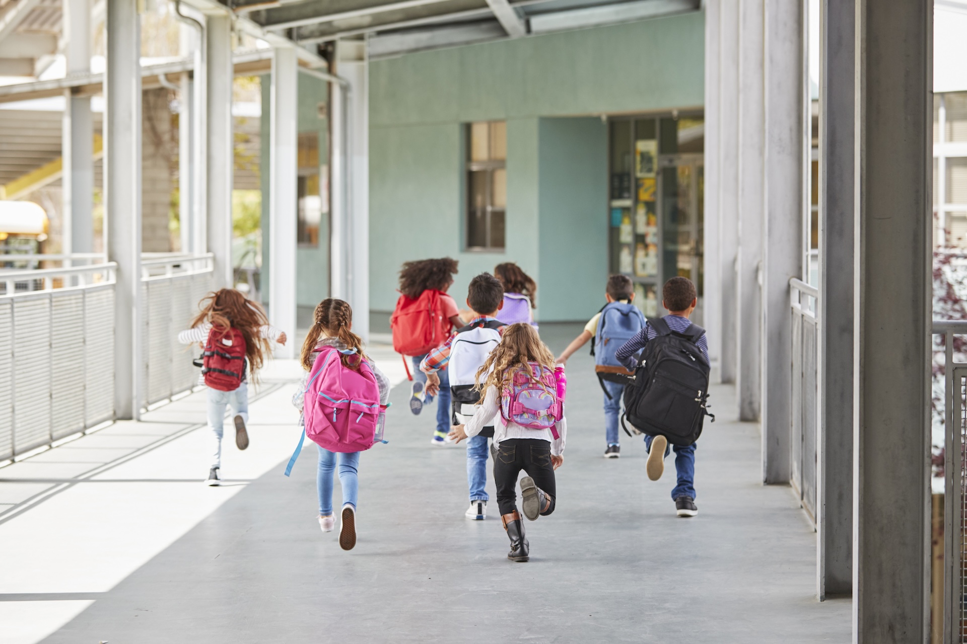 Elementary school kids run from camera in school corridor